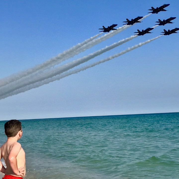 US Navy Blue Angels fly high over Pensacola Beach as a young boy watches from the shoreline